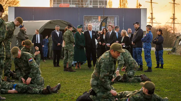 Het Koninklijk paar kijkt naar militairen die oefenen met het verzorgen van gewonden. 