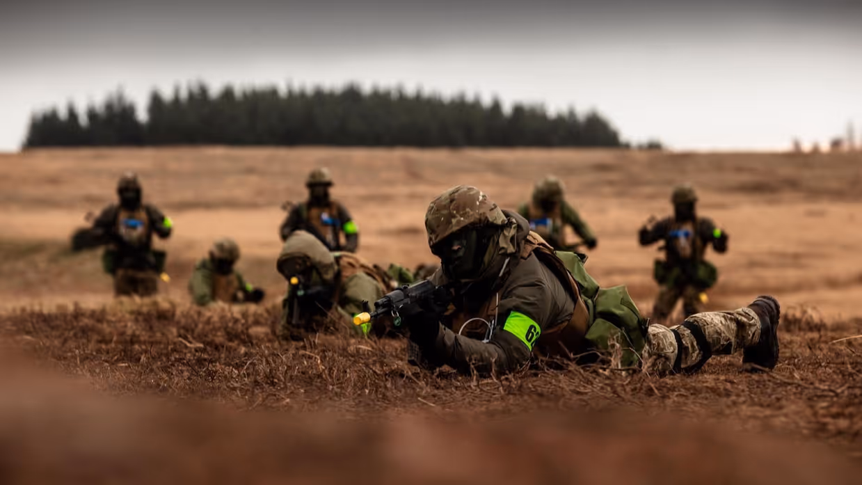 Militairen liggend in het veld, ze richten hun wapens.