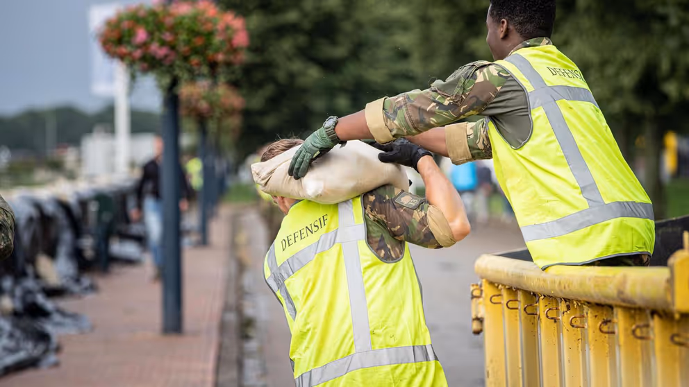 Militairen geven zandzakken door.