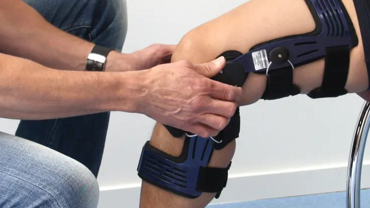 Een brace wordt om een knie gezet.