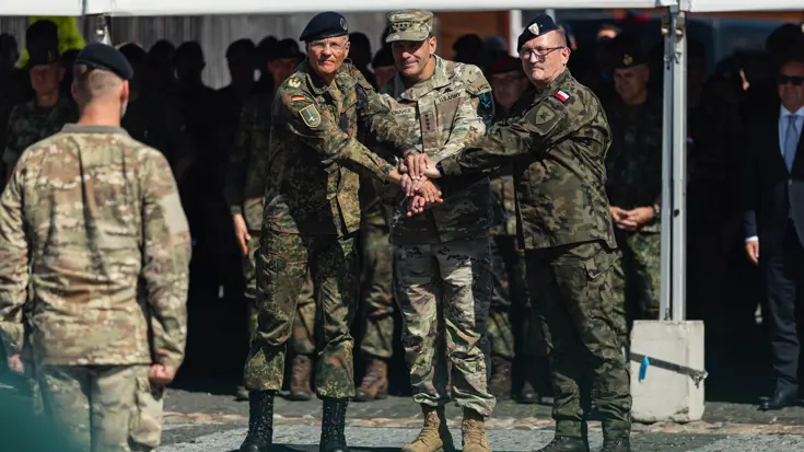 Drie internationale militairen leggen handen op elkaar als teken van eenheid.
