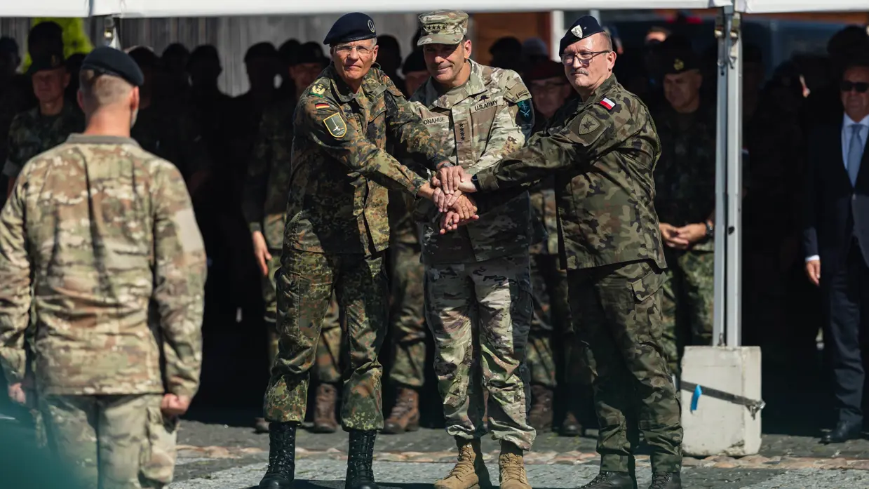 Drie internationale militairen leggen handen op elkaar als teken van eenheid.