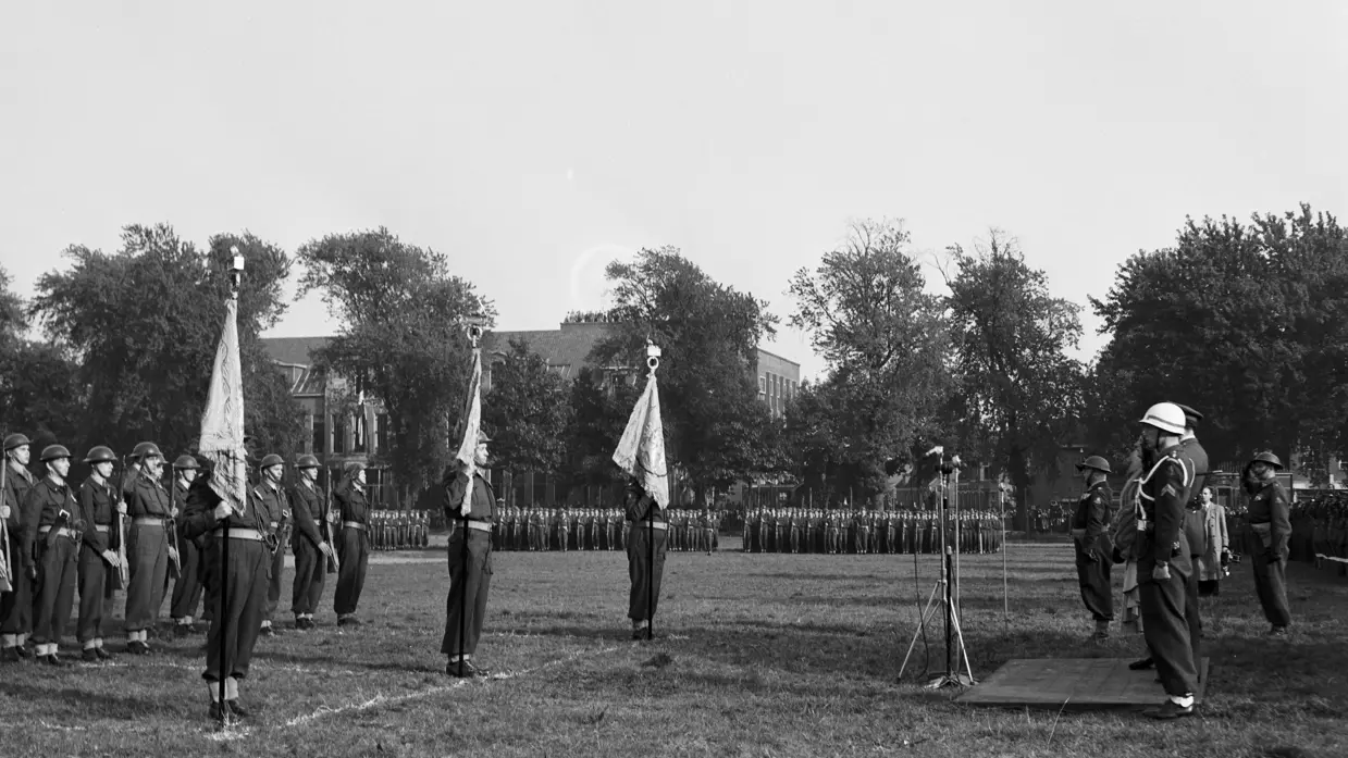 Militairen staan met vaandel opgesteld.
