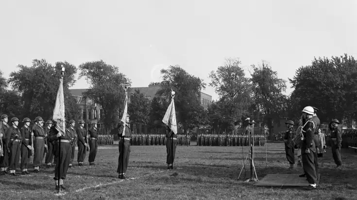 Militairen staan met vaandel opgesteld.