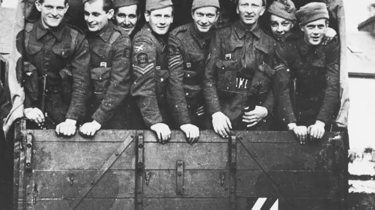 Zwart-witfoto commando's die achterin een voertuig staan.