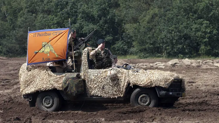 Een militair salueert vanuit een Mercedez-Benz-jeep.