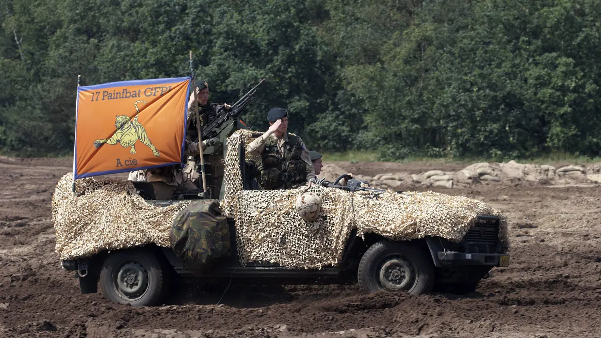 Een militair salueert vanuit een Mercedez-Benz-jeep.
