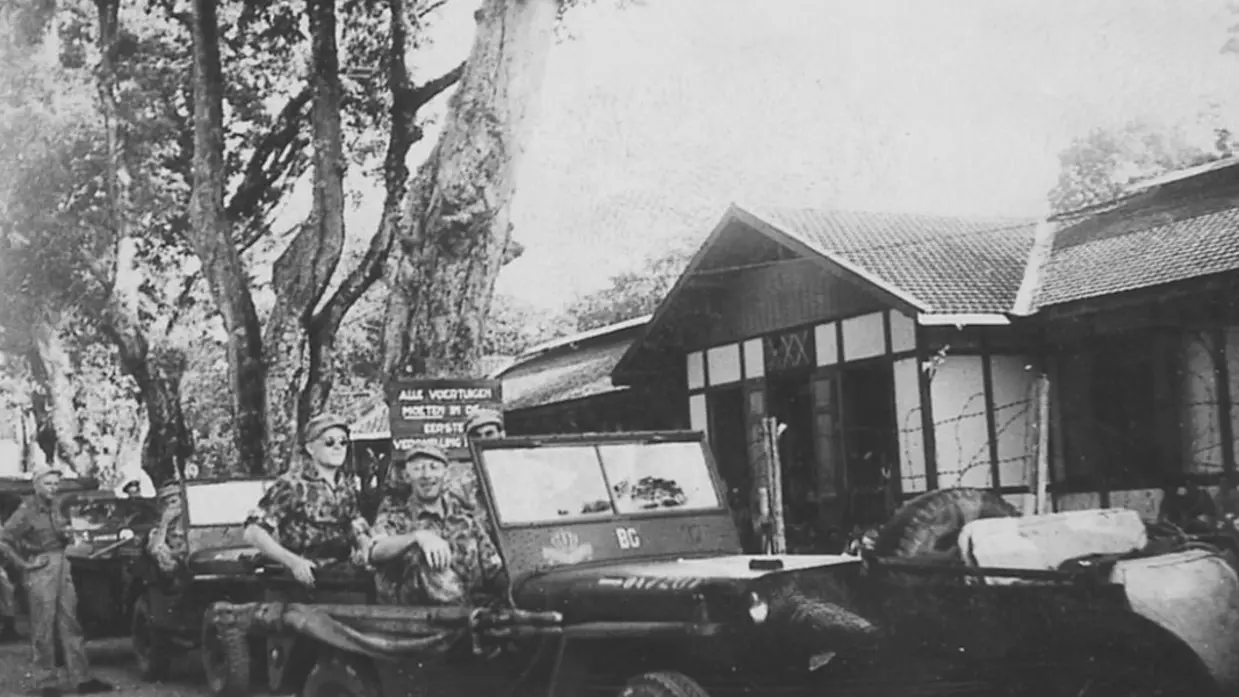 Nederlandse militairen rijden in jeeps door de straten in Indonesië.
