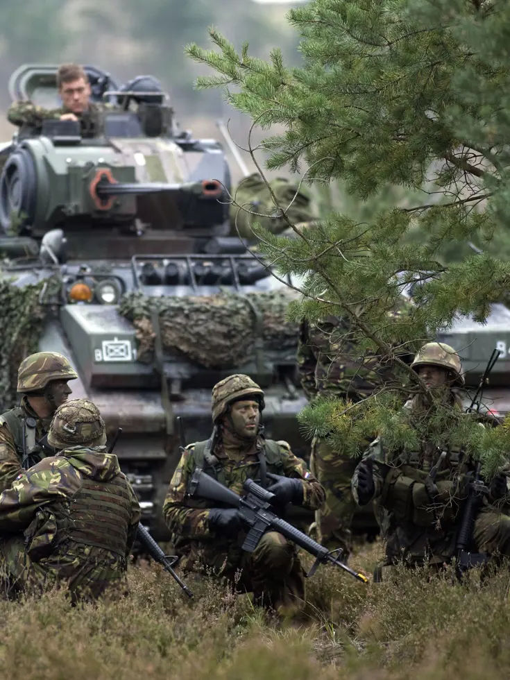 Militairen bij een rupsvoertuig tijdens en oefening.