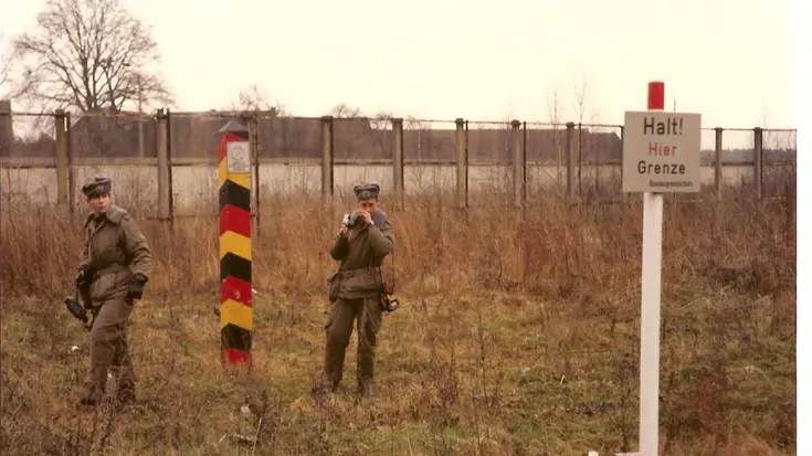 2 militairen naast een grenspaal voor de Berlijnse Muur.