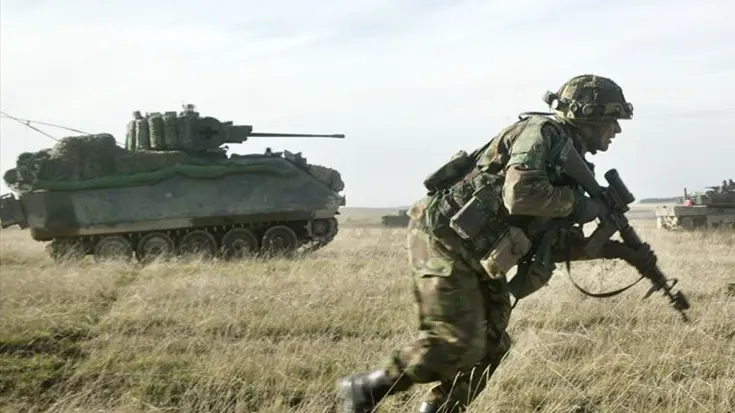Militair tijdens een oefening met op de achtergrond een CV90.