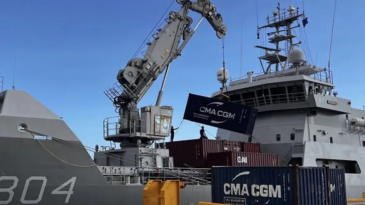 Zeecontainers worden aan boord van marineschip Zr.Ms. Pelikaan gehesen met een kraan.