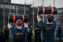 2 mannen op de rug gezien houden dikke zwarte rol boven hun hoofd.