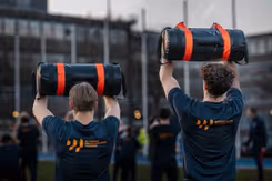 2 mannen op de rug gezien houden dikke zwarte rol boven hun hoofd.