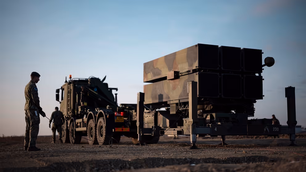 2 militairen staan bij een luchtafweersysteem. 