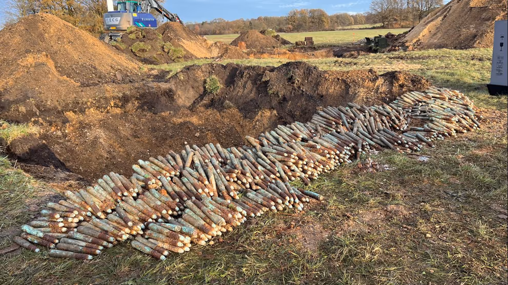 Grote hoeveelheid  opgestapelde granaten in grasland.