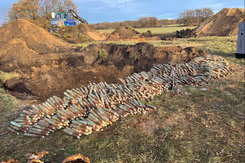 Grote hoeveelheid  opgestapelde granaten in grasland.