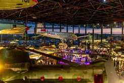 Bovenaanzicht van museumvloer met vliegtuigen die aan het plafond zijn bevestigd en mensen eronder.