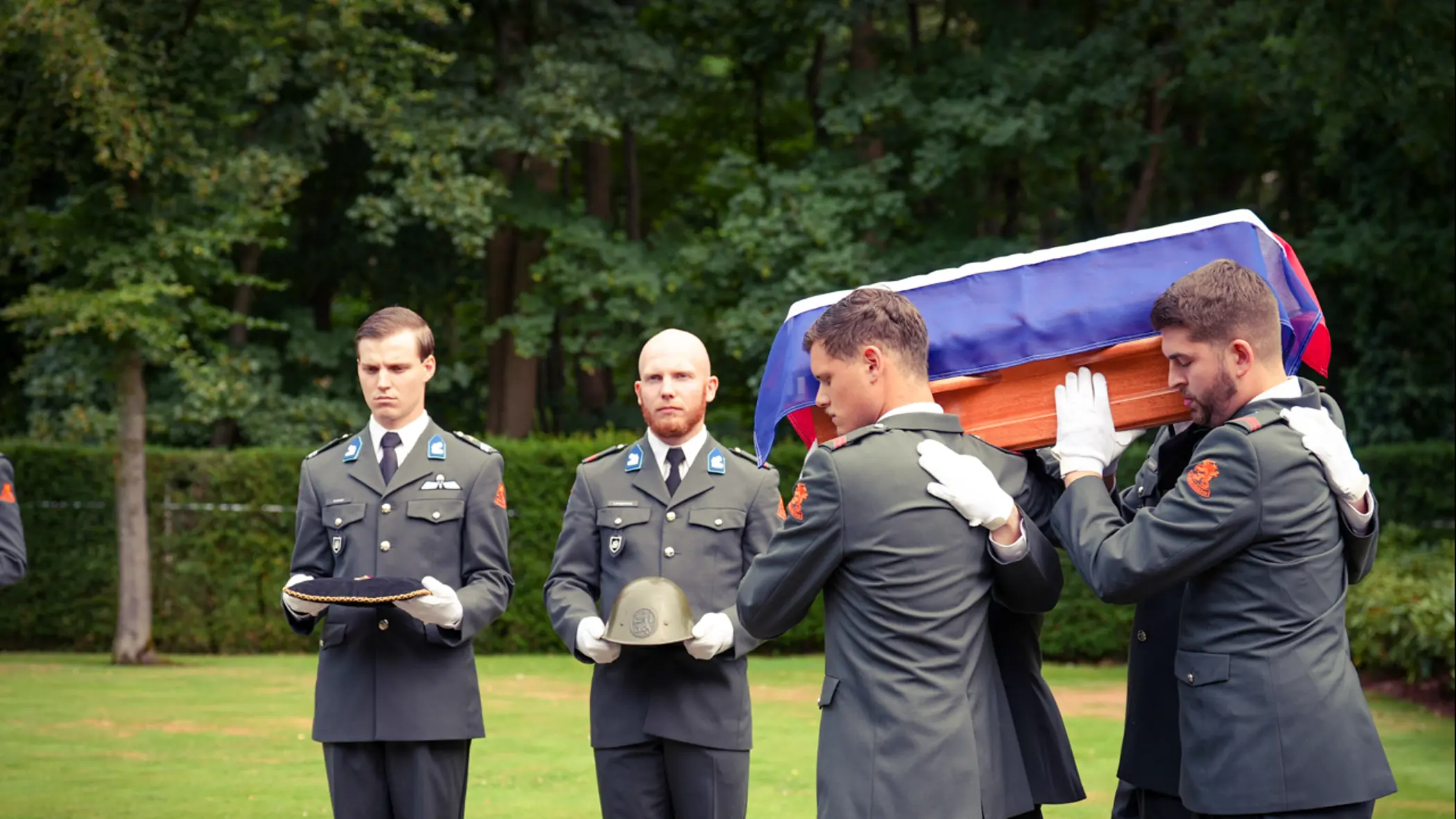 Militairen dragen de kist met het stoffelijk overschot.