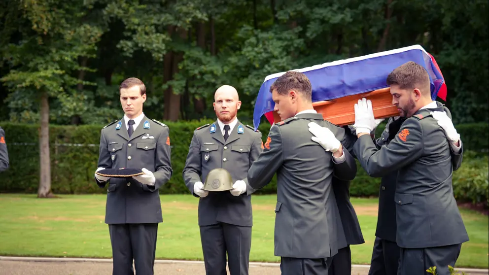 Militairen dragen de kist met het stoffelijk overschot.