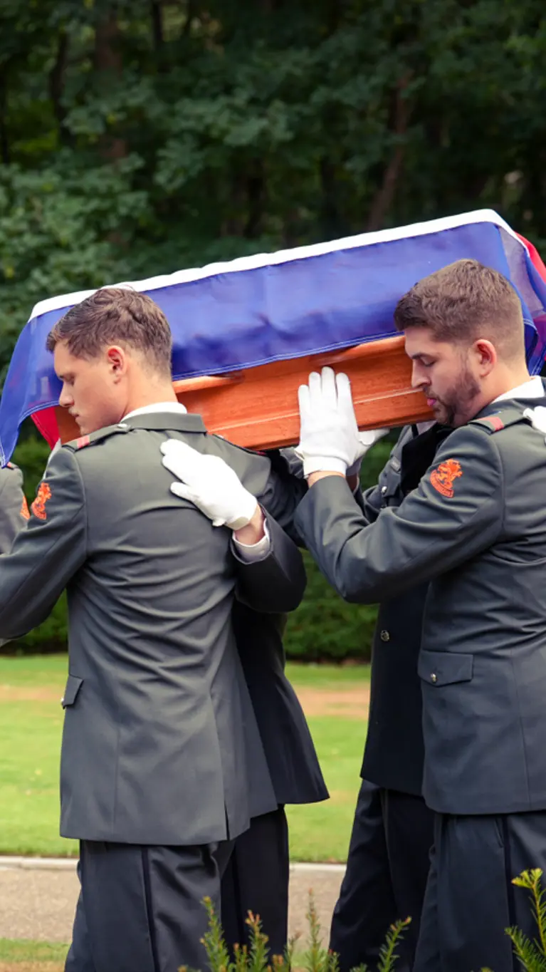 Militairen dragen de kist met het stoffelijk overschot.