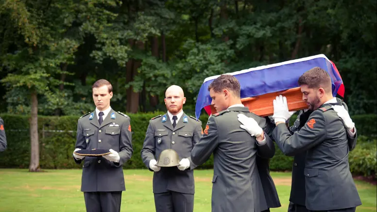 Militairen dragen de kist met het stoffelijk overschot.