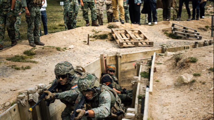 Brekelmans kijkt naar militairen die trainen in loopgraven.