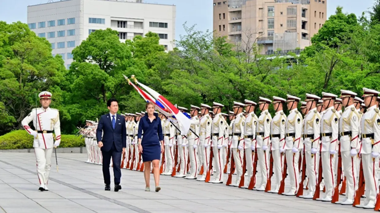 De ministers lopen langs Japanse militairen. 