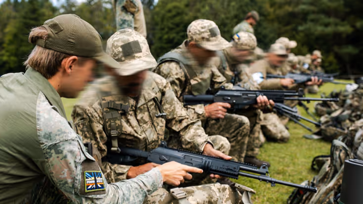 Militairen krijgen uitleg op een lang wapen.