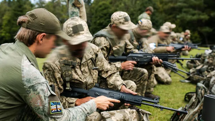 Militairen krijgen uitleg op een lang wapen.