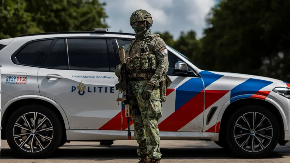 Militair poseert voor een politieauto.