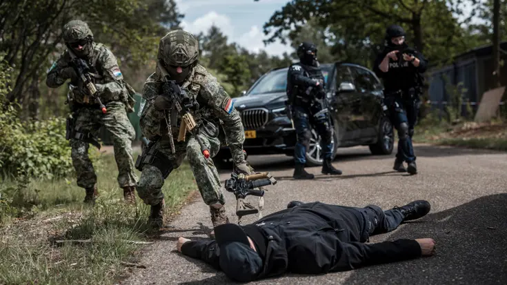 Militairen pakken een wapen af van een gefingeerde verdachte.