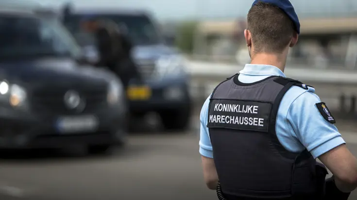 Een marechaussee staat paraat bij een luchthaven.