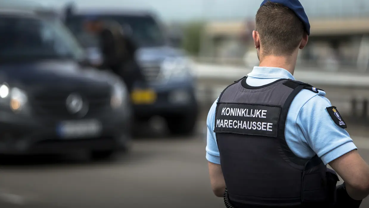 Een marechaussee staat paraat bij een luchthaven.