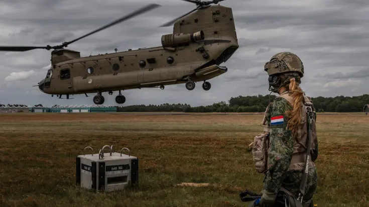 Prinses Amalia staat bij een opstijgende Chinook-helikopter.