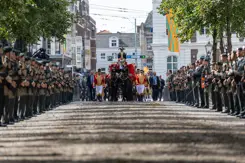 De Koninklijke stoet omringt door militairen. 
