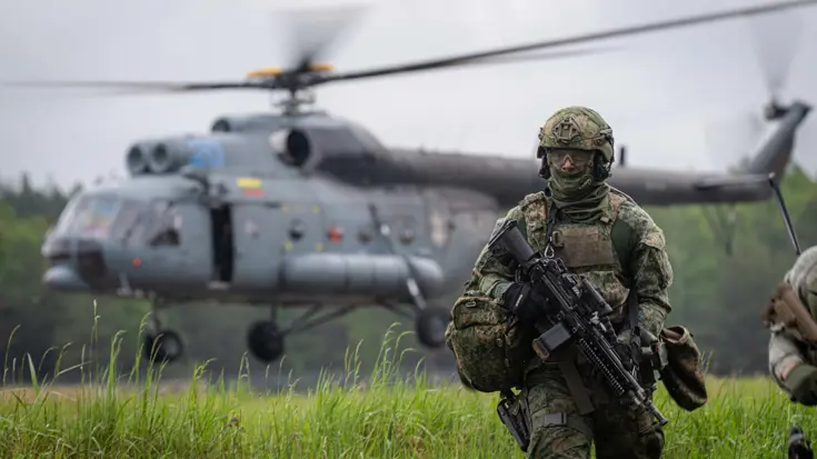 Helikopter met draaiende rotorbladen. Op voorgrond militair.