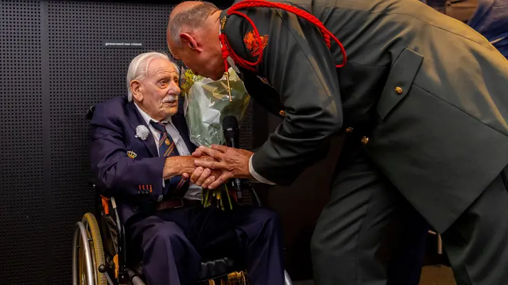 Veteraan in een rolstoel krijgt een bos bloemen.