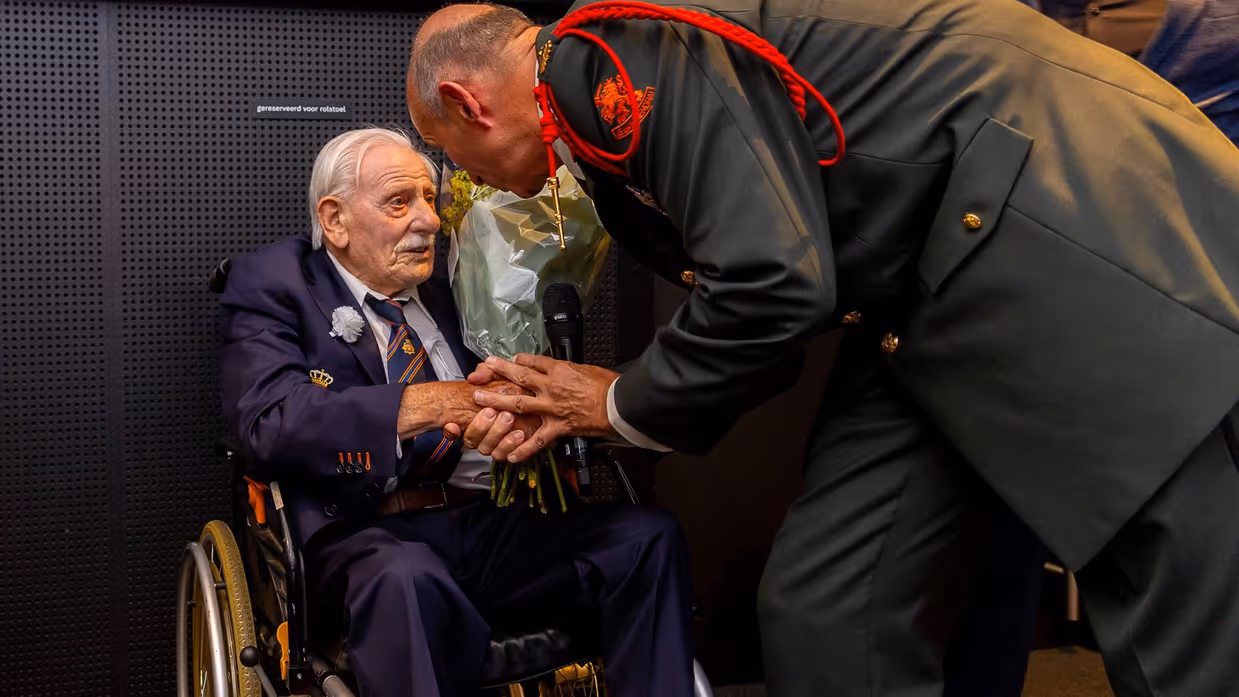 Veteraan in een rolstoel krijgt een bos bloemen.
