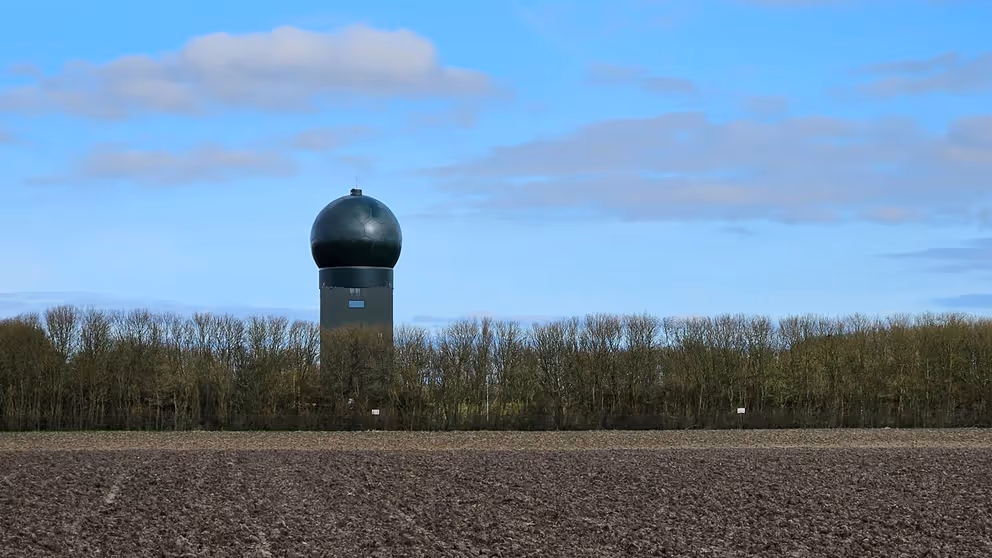 Het radarstation in Wier achter een rij kale bomen.
