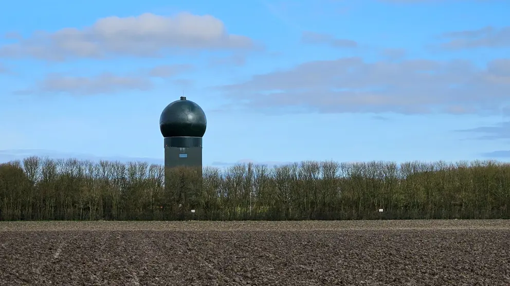 Het radarstation in Wier achter een rij kale bomen.