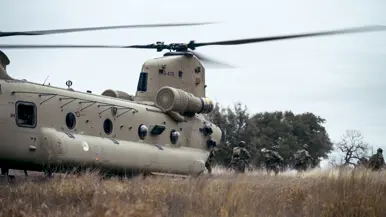 Militairen verlaten via de achterklep een Chinook in het veld.