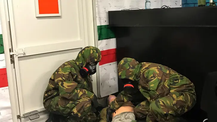2 militairen met beschermend masker onderzoeken een gewonde in een Italiaans restaurant.