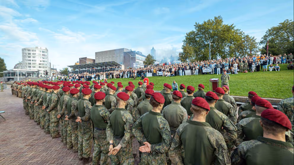 Militairen met rode baretten op staan in het gelid tijdens ceremonie.