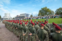 Militairen met rode baretten op staan in het gelid tijdens ceremonie.