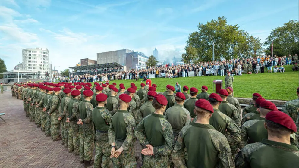 Militairen met rode baretten op staan in het gelid tijdens ceremonie.