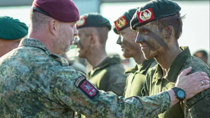Hoge militair legt hand op schouder andere militair ter felicitatie bij ceremonie.