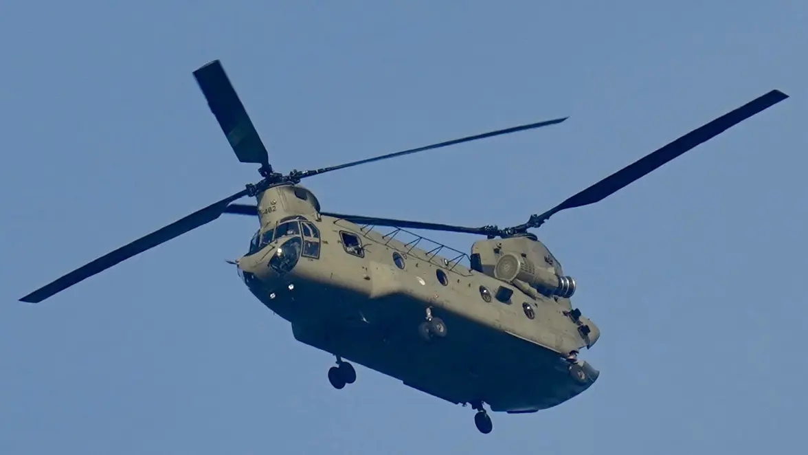 Een Chinook-helikopter vliegt in de blauwe lucht. 