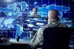 Militairen zitten achter beeldschermen waar de wereldkaart op staat.