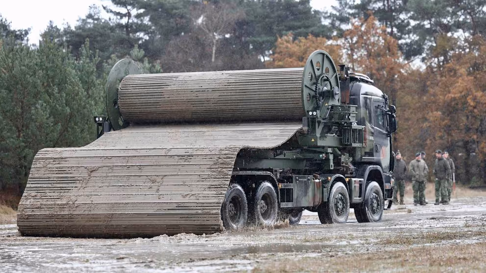 Wegenmattenlegger staat geparkeerd aan rand van bos.